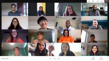 A view of a screen showing sixteen people attending an online meeting, smiling and waving