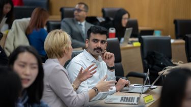 MBA students talking to each other in a lecture theatre.