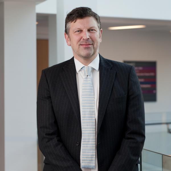 Profile picture of A head and shoulders photo of Andrew Smith wearing a black suit, white shirt and light blue tie.