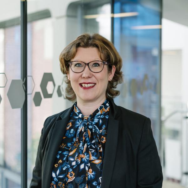 Profile picture of Melanie Hassett wearing a patterned top and black jacket.