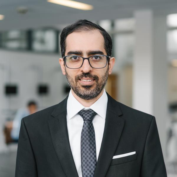 Profile picture of Amin Vafadarnikjoo wearing a white shirt, black checked tie and black jacket.
