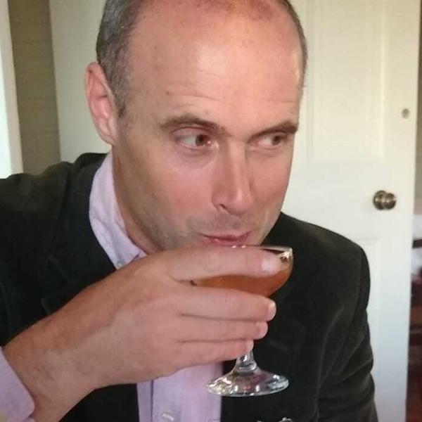 Profile picture of A photo of Dominic Gregory sipping a drink at a table.