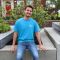 Dario Trimarchi in blue University of Sheffield student ambassador t shirt, sitting outside HRI building and smiling at camera