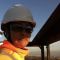 Shot of Bhavini at work in a hard hat and hi vis jacket.