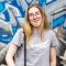 Student Molly standing against a colourful wall of street art