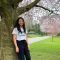 A student stands in front of a blossom tree. They are wearing a University of Sheffield t-shirt