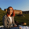 Ines, sat in a field, with houses in the background on a clear day.