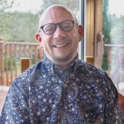 Man with glasses smiling at camera sitting on a chair
