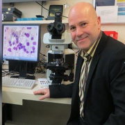 John Snowden, male sits at desk with microscope