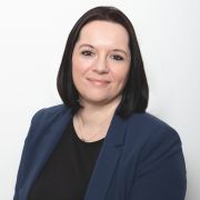 A headshot of Sandie Buchan wearing a black top and a blue blazer.