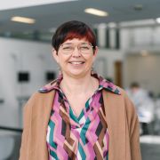 Karina Nielsen wearing a colourful patterned top and sandy brown jacket.