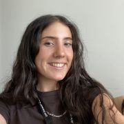 A selfie of a Caucasian woman with long brown hair against a white background
