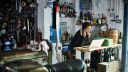 Woman talking on phone and looking at laptop in motorcycle workshop, motorcycle in foreground.