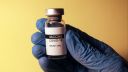 Gloved hand holding a COVID-19 vaccine