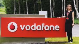Laura Craciun, computer science alumni standing by a Vodafone sign