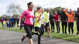 A family of mixed ages running a race being cheered on by spectators