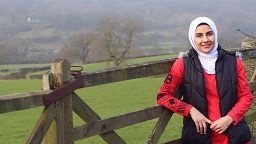 Qutouf Al Kindi in the countryside leaning against a fence