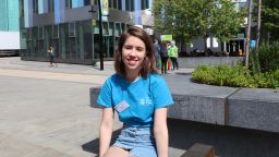 Student ambassador Sophie sitting in the sun and smiling outside Jessop West Building