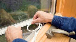 a pair of hands fits insulation to a window
