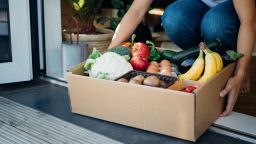 Cropped shot of young woman receiving a box of fresh organic food delivery at the front door.