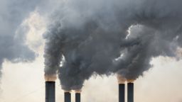 The tops of five chimneys with smoke coming out of them.