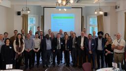 Attendees of the AREC workshop stood together in front of a powerpoint presentation
