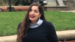 Loukia smiling, in front of the playing fields at the University