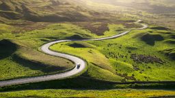a road through the green hills of the peaks