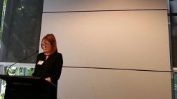 A presenter giving a speech at a stand