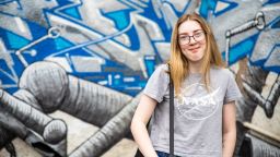 Student Molly standing against a colourful wall of street art