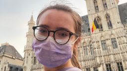 student in Brussels' main square with Belgian flag in the background