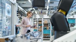 An engineer looking at a tablet next to a production line inside a factory