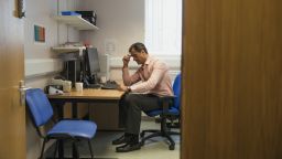 A GP sat in their office with a worried expression