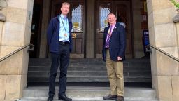 Two male staff stand in front of Firth Court entrance