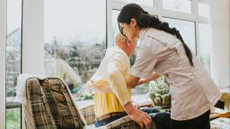 A carer helping an elderly woman stand up