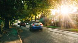 Cars on a tree-lined suburban road in the UK