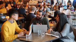 A group of students working on laptops over a coffee.