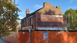 Henderson's House with signs on front and side, and orange and black hoardings around it
