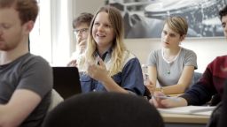 A girl with blonde hair talks during a seminar