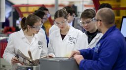 A group of students gather around a member of staff