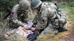 Two military medics providing medical treatment to a soldier injured during combat