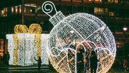 a group of people stand in a large lit-up christmas bauble. 