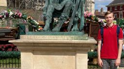 Postgraduate student Lewis beside a statue