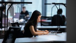 A person working on a laptop, sitting at a desk.