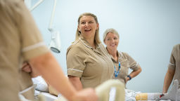 A group of nursing apprentices stood next to a hospital bed