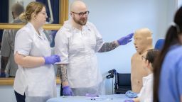 Three student nurses practice their clinical skills on an NG tube manikin