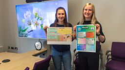 Two student ambassadors holding up the winning posters