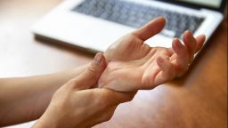 A lady holding her hands while suffering from pain