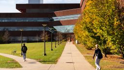 Students walking towards a building on Penn State's campus with lots of green spaces and trees around them
