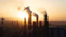 Emissions being released from a chemical plant against a glowing skyline